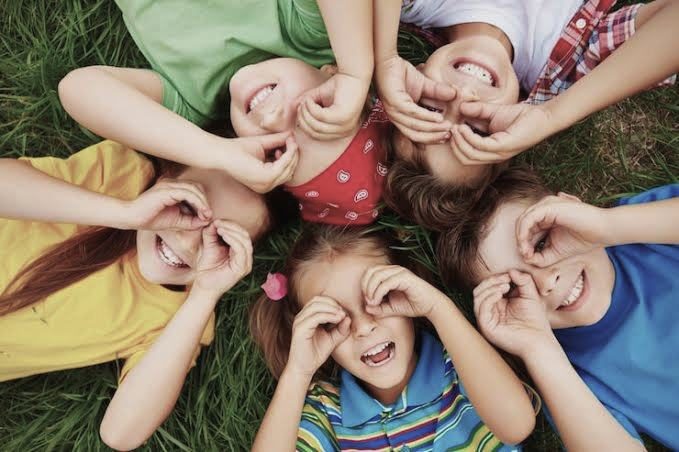 Children lying in the grass, smiling together