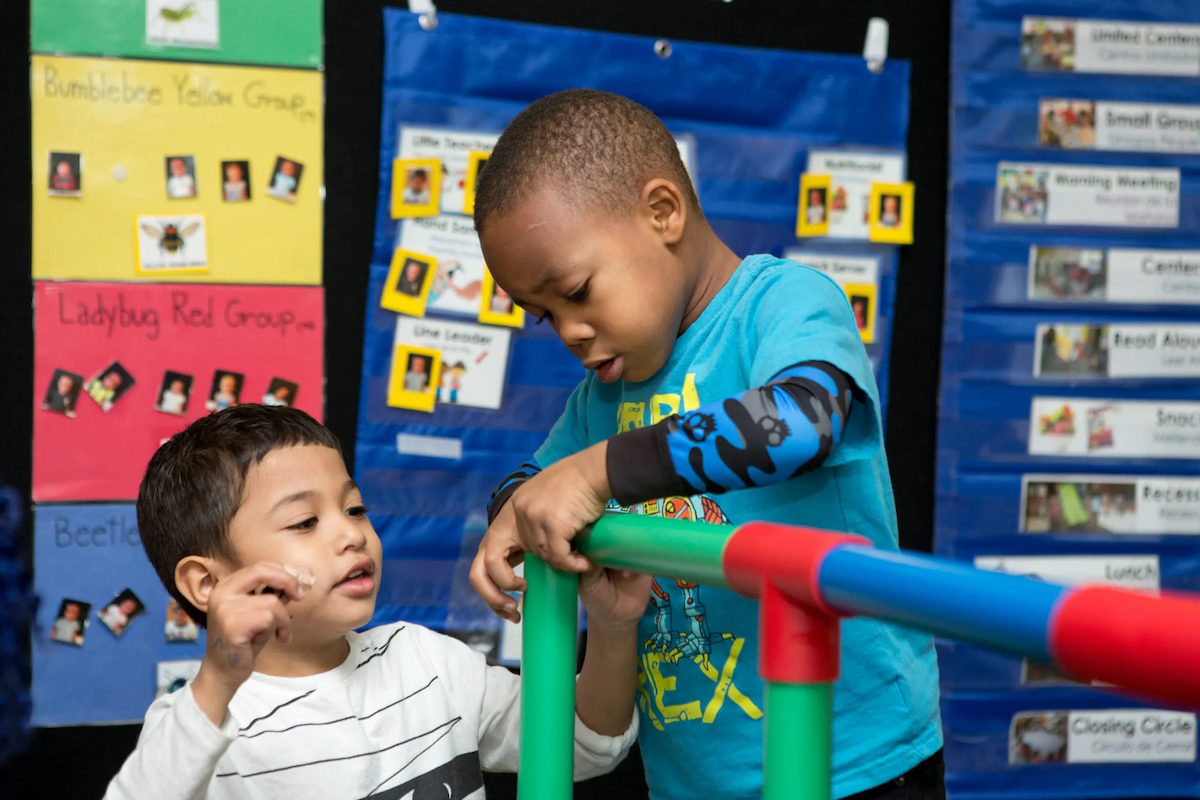 An educator building with blocks alongside a preschooler